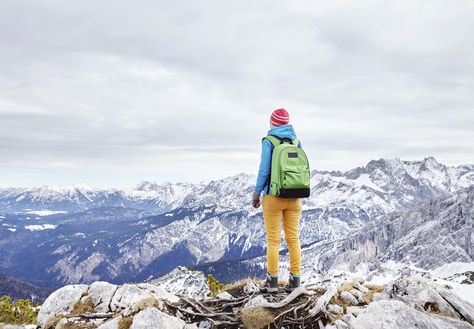 Female hiker with backpack standing on top of mountain